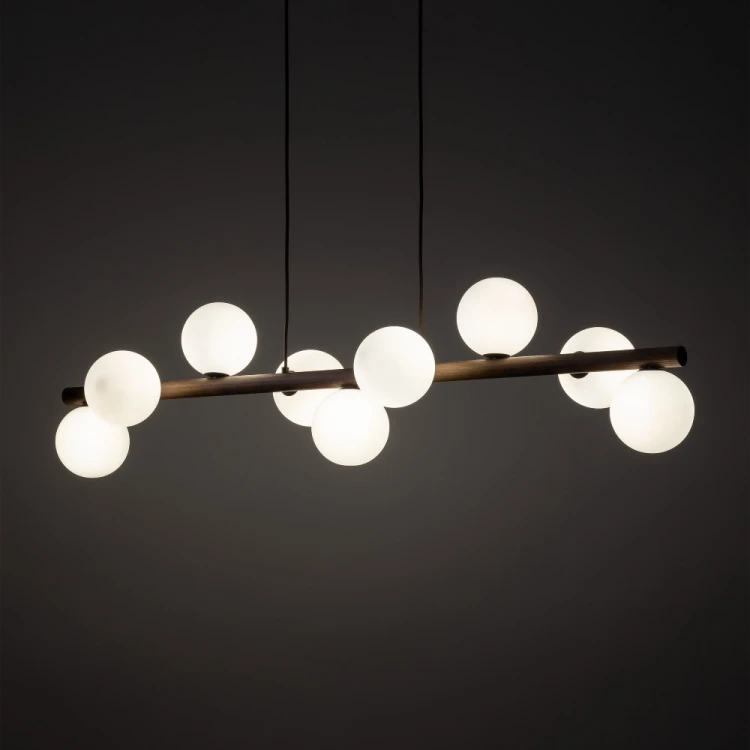 Lampa wisząca ESTERA WOOD 9 × G9 rozświetli stół w jadalni lub wyspę kuchenną. Białe szklane klosze kontrastują ze stelażem w kolorze orzecha. Model 10273 ma 117 cm długości, stopień ochrony IP20 i nie zawiera żarówek.