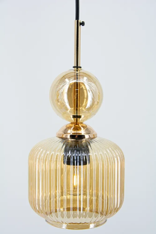 NADIA Elem to lampa wisząca z trzema ryflowanymi kloszami i dekoracyjnymi kulami. Połączenie czerni, złota i bursztynowego szkła pasuje do wnętrz glamour i modern classic. Model 3×E27, szerokość 65 cm, regulacja wysokości 30–90 cm.