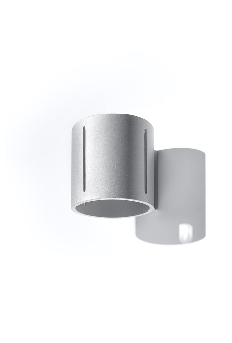 Nowoczesny kinkiet INEZ w kolorze szarym, zamontowany na ścianie. Światło sączy się w górę, w dół oraz przez boczną perforację, tworząc efektowny wzór świetlny. Idealny do wnętrz w stylu nowoczesnym, industrialnym i loftowym