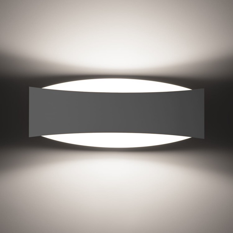 Nowoczesny biały kinkiet TONI o podłużnej formie, zamontowany na ścianie. Emituje światło w górę i w dół, tworząc elegancki efekt świetlny. Idealny do korytarza, salonu lub sypialni w minimalistycznym, nowoczesnym stylu