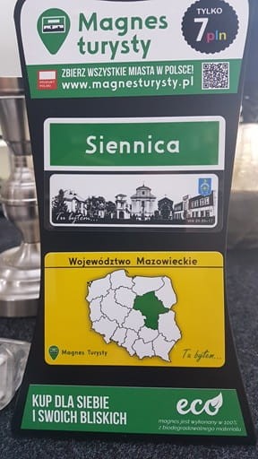 Magnes Turysty SIENNICA 05-332 przedstawia zabytki i budynki Siennicy w formie znaku „teren zabudowany”. Wykonany w 100% z biodegradowalnego materiału, wymiary 8,5×6,5 cm. Produkt polski, idealny na pamiątkę lub do kolekcji