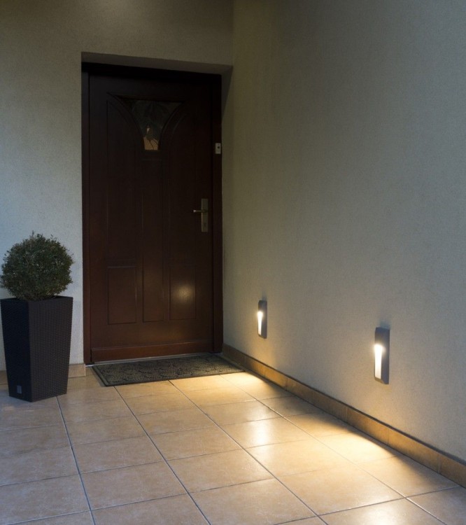 Lampa elewacyjna Mur PC 2502B w kolorze popielatym to stylowe i trwałe oświetlenie zewnętrzne. Zdjęcie przedstawia kompaktową, natynkową oprawę LED o mocy 1,5W, idealną do podświetlenia elewacji, schodów lub ogrodzenia. Wysoka szczelność IP65