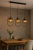 Lampa sufitowa AMARO 3xE14 Alfa 62472 to połączenie loftowego stylu i elegancji. Czarna konstrukcja, złote detale i bursztynowe klosze tworzą ciepły klimat. Idealna nad stół, do salonu lub kuchni.