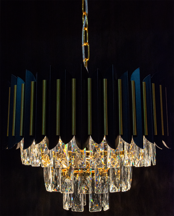 Żyrandol kryształowy RONDA 4-płomienny w czerni i złocie to połączenie elegancji i nowoczesności. Transparentne kryształy tworzą spektakularny efekt świetlny. Doskonały nad stół lub do salonu glamour. Regulowana wysokość 33–90 cm.