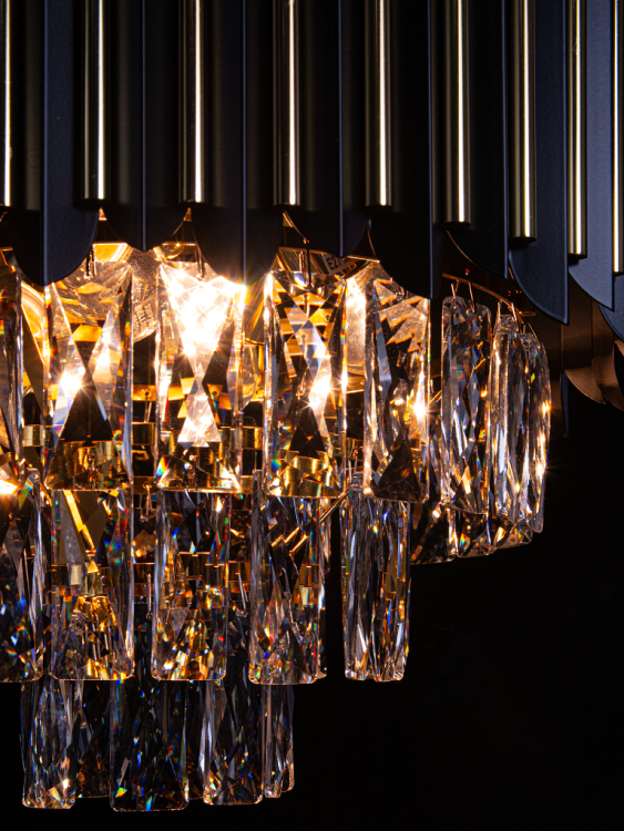 Lampa wisząca RONDA 4xE14 to ekskluzywny model glamour z czarnych paneli, złotych detali i kryształowych zwisów. Idealna do wnętrz eleganckich i nowoczesnych. Dodaje pomieszczeniu blasku i luksusowego charakteru.