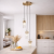Złota lampa wisząca TARASO 3xE14 łączy nowoczesny design z elegancją. Trzy szklane klosze pięknie rozpraszają światło, a regulowane zawieszenie pozwala dopasować lampę do różnych aranżacji wnętrz.