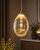 HUELTO Italux LED to designerska lampa wisząca z kloszem wypełnionym pęcherzykami powietrza. Elegancki kolor złota szampańskiego oraz ciepłe światło 3000K podkreślają charakter nowoczesnych, glamour i modern classic wnętrz.