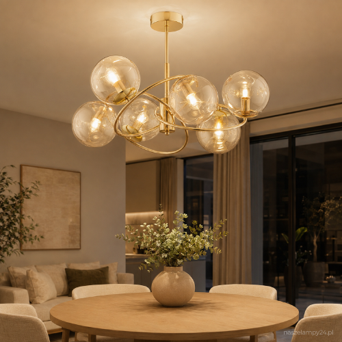 Złota lampa sufitowa WIROMAT Alfa 63219 z sześcioma bursztynowymi kulami efektownie ozdobi salon lub jadalnię. Model ma 66 cm szerokości, 40 cm wysokości oraz oprawki na 6 żarówek LED E14 o maksymalnej mocy 10 W.