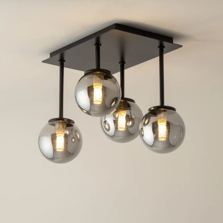 Lampa sufitowa TULIA 4xG9 czarna z dymionymi kloszami efektownie oświetli salon, jadalnię, sypialnię lub korytarz. Cztery szklane kule umieszczone na prętach o różnej długości tworzą ciekawą, przestrzenną kompozycję.