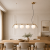 CARIMI Italux to elegancka lampa sufitowa z czterema białymi kloszami w kształcie kul. Armatura w kolorze miodowego mosiądzu ociepla aranżację, a długość 90 cm sprawia, że model świetnie prezentuje się nad dużym stołem.