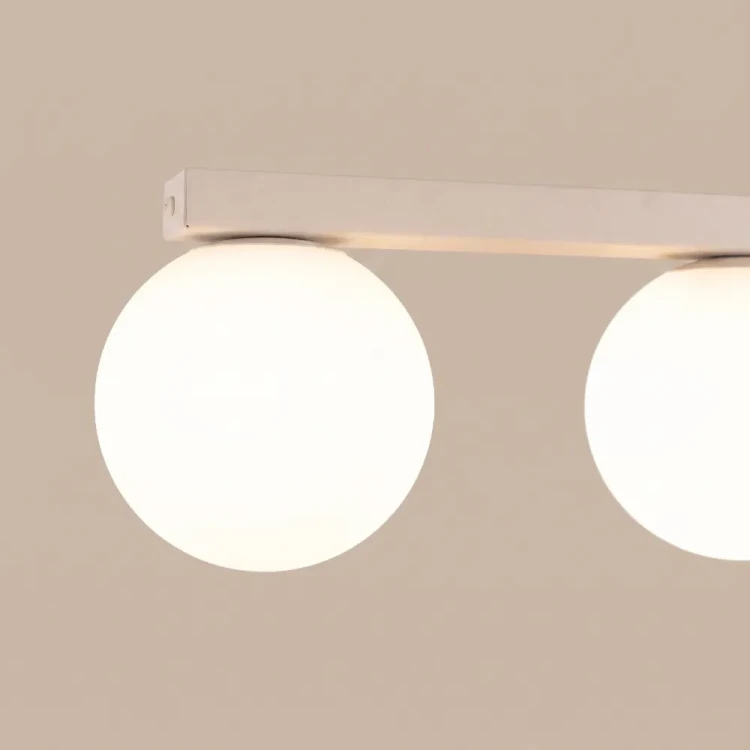 Nowoczesny plafon YOLI 4 beżowy Sollux SL.2235 ma cztery białe kule i długość 88 cm. Lampa sufitowa 4xG9 ze stali i szkła pięknie uzupełni jadalnię, kuchnię lub salon, dodając aranżacji lekkości i przytulnego charakteru.