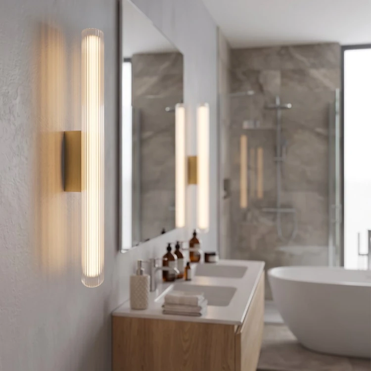 Oświetl lustro kinkietem TRIVIA GOLD w kolorze szczotkowanego złota. Smukła lampa LED 11W o długości 60 cm posiada funkcję 3CCT, strumień 930 lm i klasę IP44. Pasuje do łazienek glamour, nowoczesnych i modern classic.