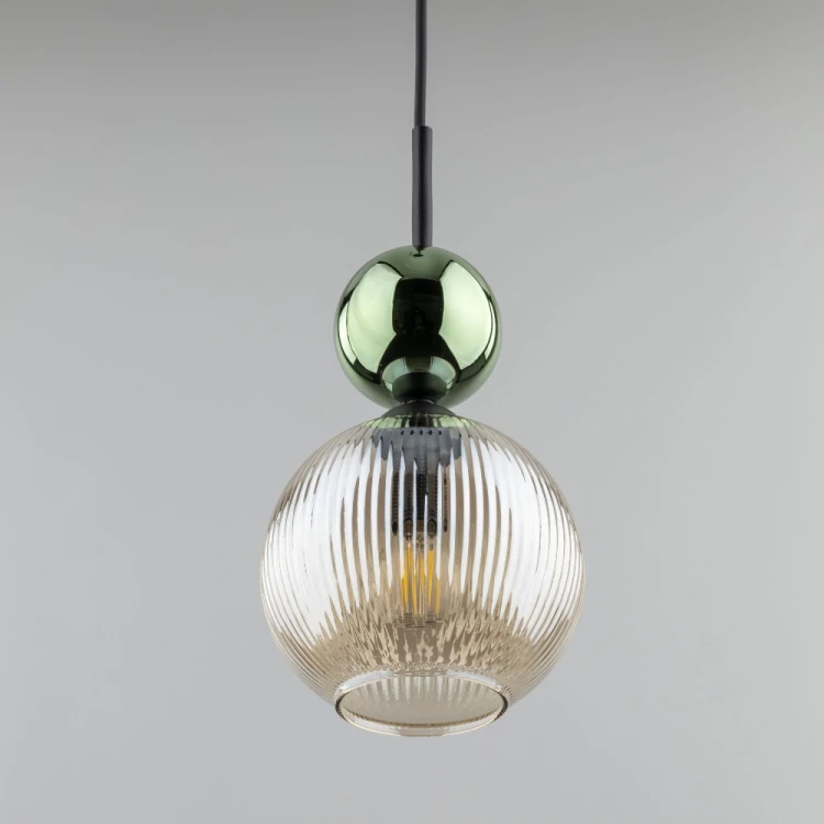 Pojedyncza lampa wisząca SOPHIA 11145 pasuje nad blat, wyspę, barek lub stolik nocny. Koniakowy szklany klosz, zielona kula i czarne elementy tworzą eleganckie połączenie w stylu glamour.
