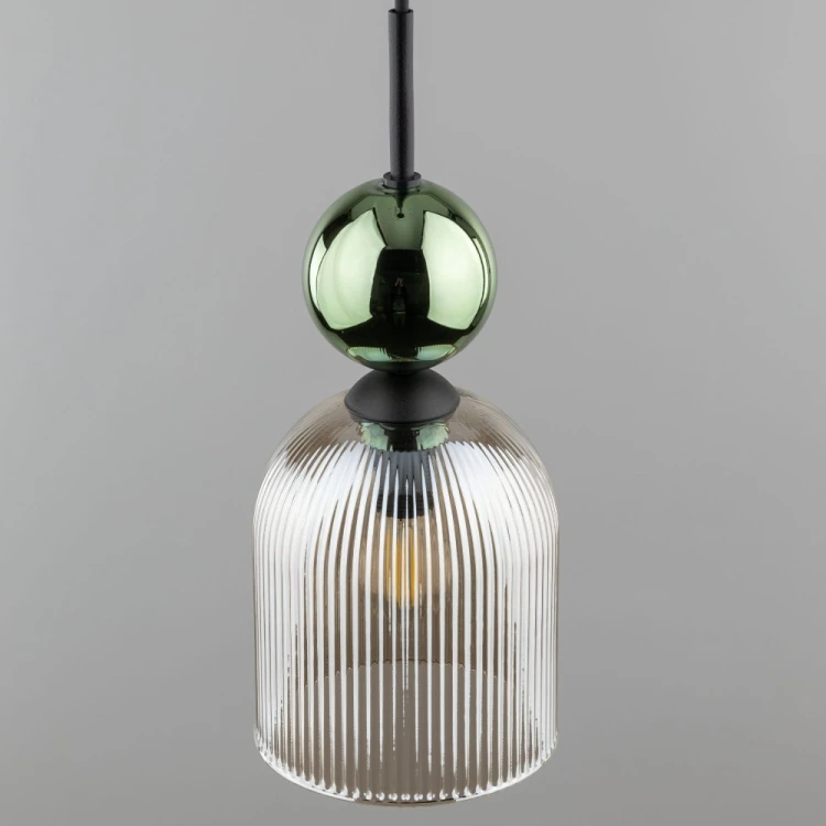 Pojedyncza lampa wisząca SOPHIA 11146 pasuje nad blat, wyspę, barek lub stolik nocny. Koniakowy szklany klosz, zielona kula i czarne elementy tworzą eleganckie połączenie w stylu glamour.